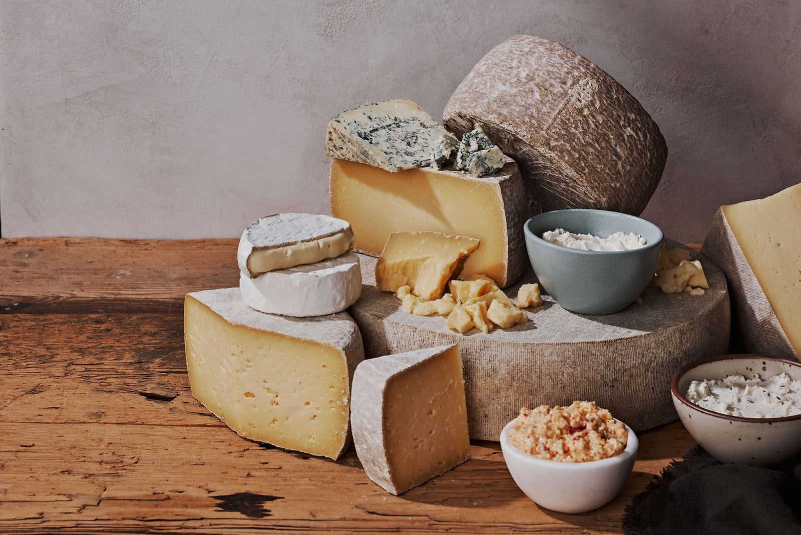 cheese wheel, wedges of cheese, and bowls of grated cheese